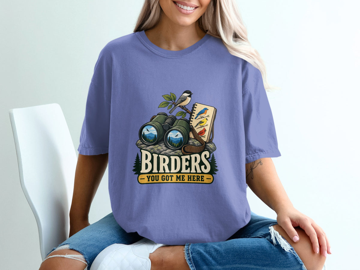 Birders You Got Me Here graphic with binoculars, birds, and notebook on a purple t-shirt.