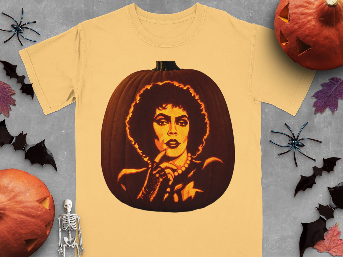 A yellow t-shirt featuring a lit jack-o'-lantern carved with the face of Dr. Frank-N-Furter, surrounded by Halloween decorations.
