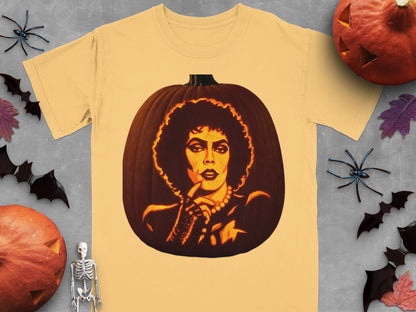 A yellow t-shirt featuring a lit jack-o'-lantern carved with the face of Dr. Frank-N-Furter, surrounded by Halloween decorations.