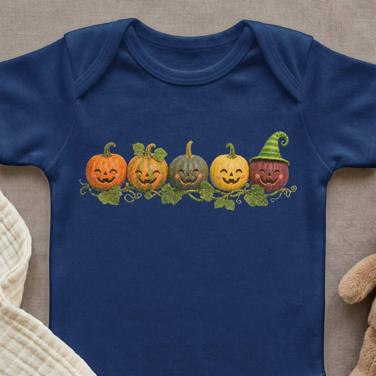 Navy blue baby onesie with a row of smiling cartoon pumpkins and vines.