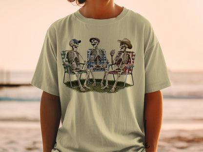 Three skeletons relax in lawn chairs, one wearing a cowboy hat, on a grassy patch.