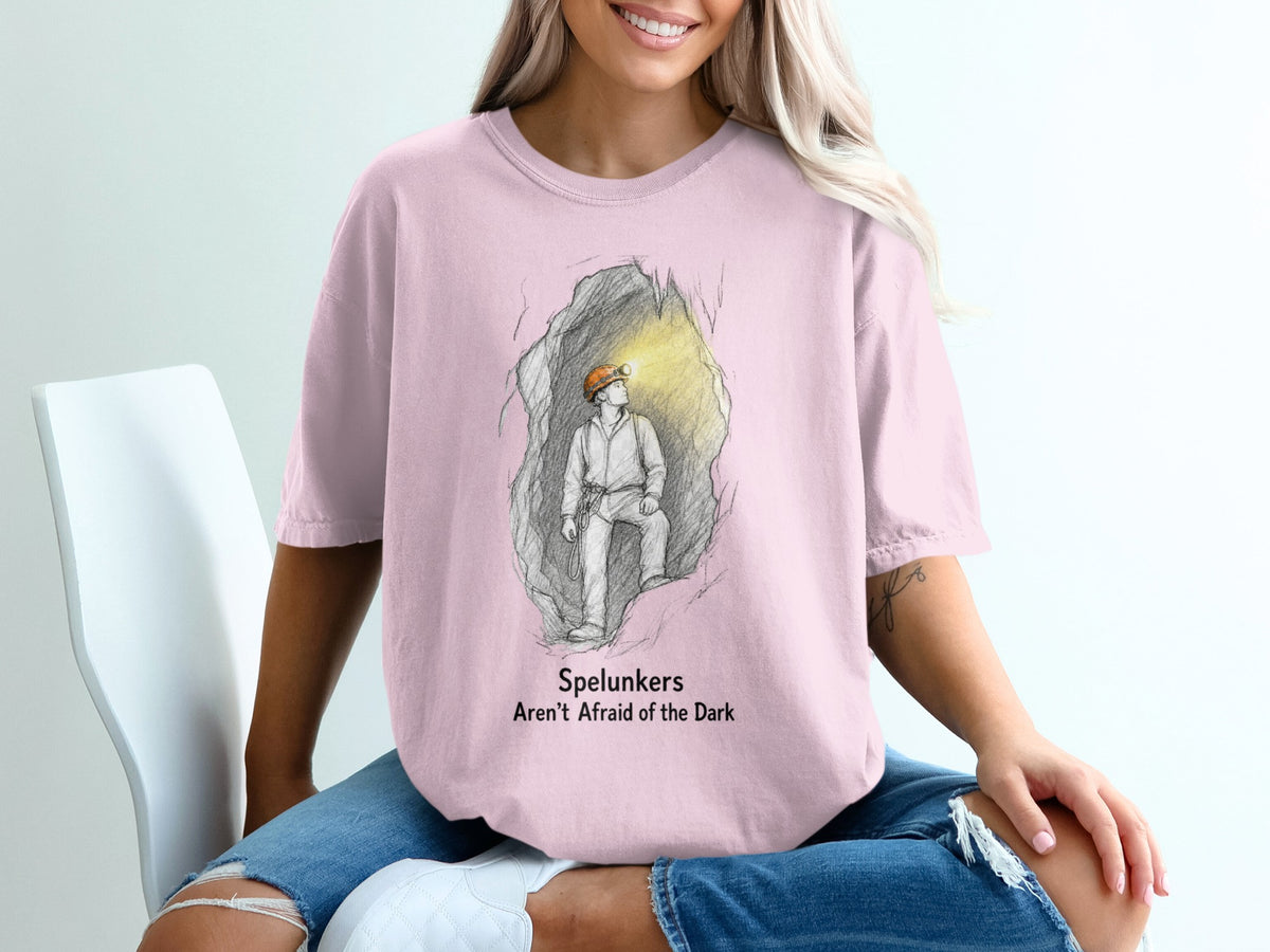 Pink t-shirt with illustration of a spelunker in a cave and text "Spelunkers Aren't Afraid of the Dark".