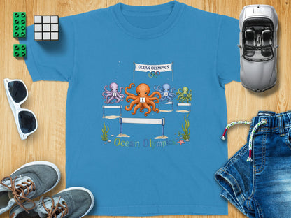 T-shirt graphic of octopuses racing under "Ocean Olympics" banner with hurdles.