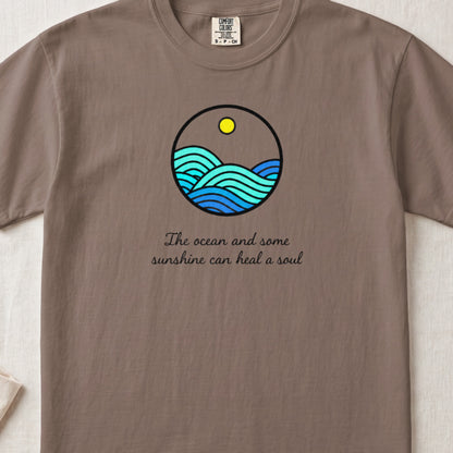 Brown t-shirt featuring a circular ocean graphic with a yellow sun and text reading The ocean and some sunshine can heal a soul.