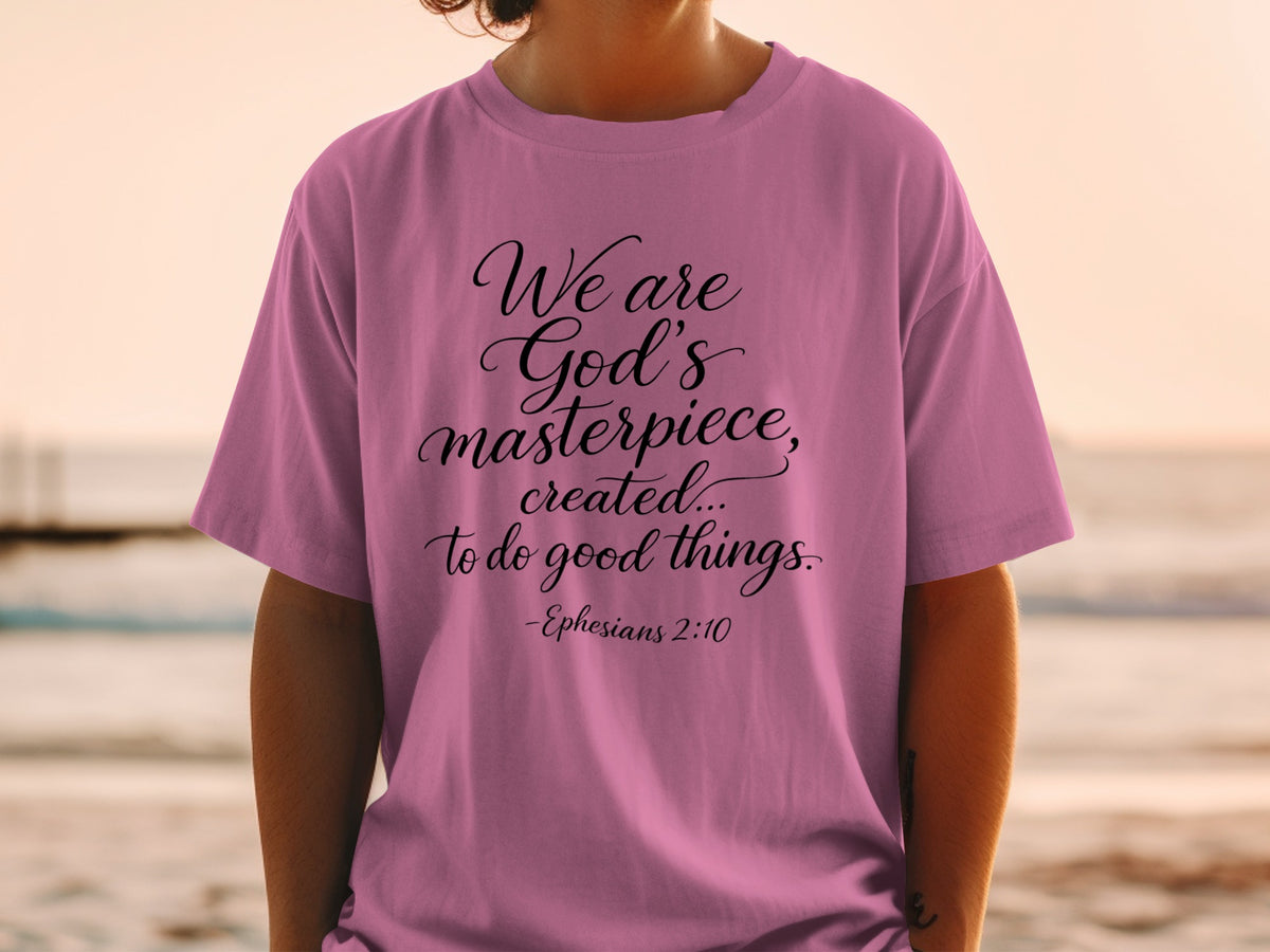 Pink t-shirt with script text "We are God's masterpiece, created... to do good things. -Ephesians 2:10".